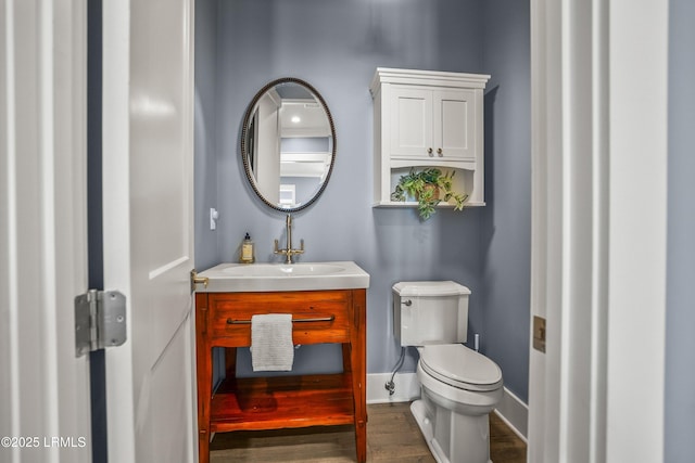 bathroom with toilet, vanity, baseboards, and wood finished floors