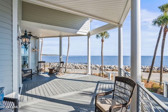 wooden terrace with a water view and a ceiling fan