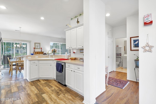 kitchen featuring stainless steel dishwasher, a peninsula, light wood-style flooring, and white cabinets