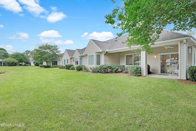 back of house with a patio area, ceiling fan, a yard, and roof with shingles