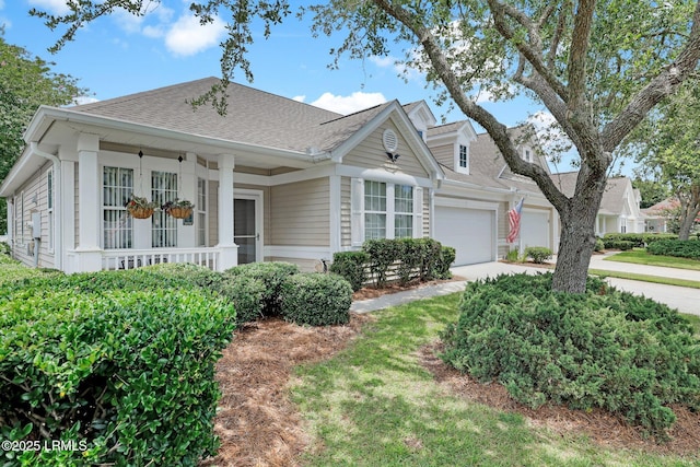 view of front of house featuring covered porch, a garage, driveway, and a shingled roof