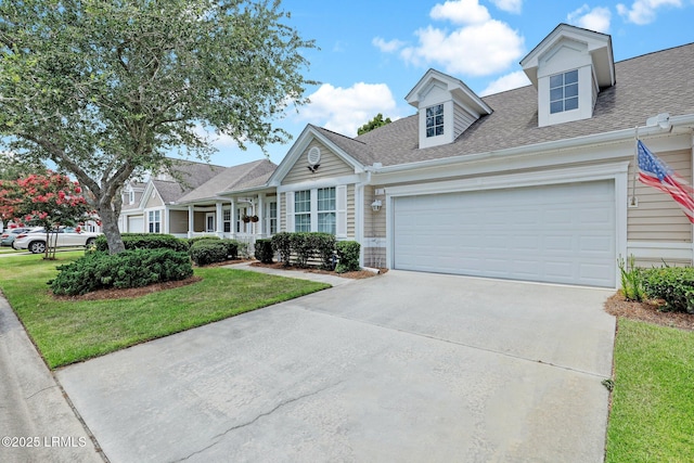 new england style home with a front yard, an attached garage, roof with shingles, and driveway