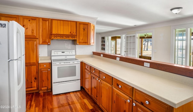 kitchen with white appliances, dark wood-type flooring, ornamental molding, and kitchen peninsula