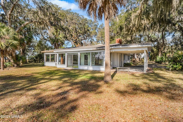 back of house featuring a carport, a yard, and a sunroom