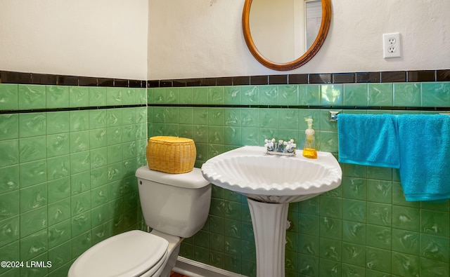 bathroom featuring toilet, sink, and tile walls