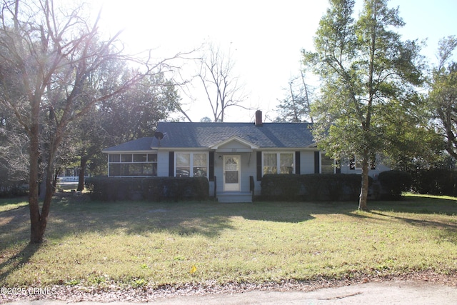 ranch-style home with a front yard, a sunroom, and a chimney