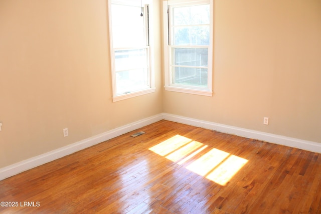 empty room with visible vents, baseboards, and hardwood / wood-style floors