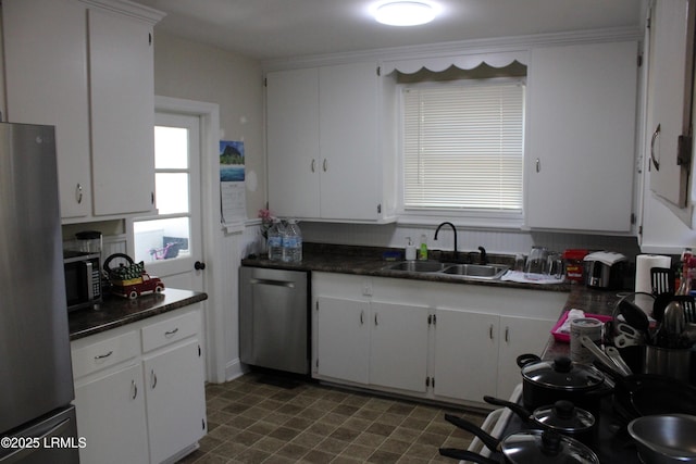 kitchen with stainless steel appliances, dark countertops, white cabinets, and a sink