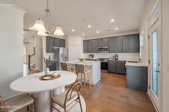423 Parkside Commons, Bluffton, SC 29910 - kitchen with stainless steel appliances, a center island, a breakfast bar, gray cabinetry, and light countertops