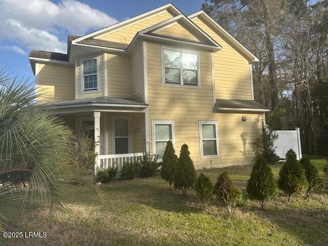 view of side of property with fence, a porch, and a lawn