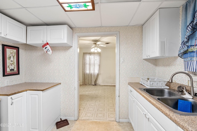 kitchen with white cabinetry, sink, a drop ceiling, and ceiling fan