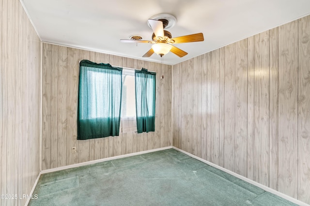 carpeted empty room featuring ceiling fan and wood walls