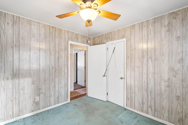 spare room featuring ceiling fan, wooden walls, and carpet floors