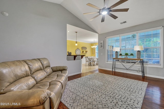 living area with baseboards, visible vents, dark wood-style floors, high vaulted ceiling, and ceiling fan with notable chandelier