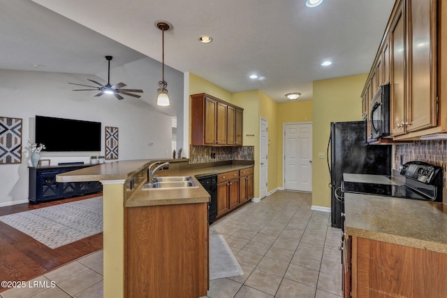 kitchen with brown cabinets, a breakfast bar, open floor plan, black appliances, and a sink