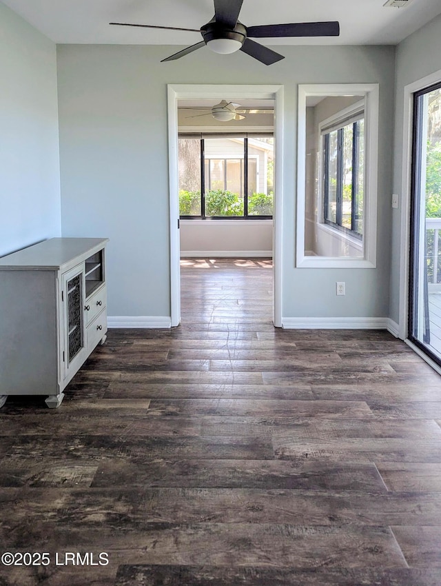 unfurnished dining area featuring baseboards, ceiling fan, and dark wood-type flooring