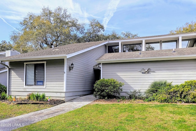 view of front of property with a front lawn and a shingled roof