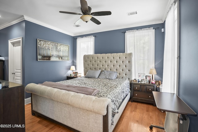 bedroom featuring crown molding, visible vents, and wood finished floors