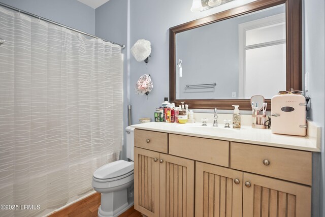 full bathroom with shower / bath combo with shower curtain, toilet, wood finished floors, and vanity