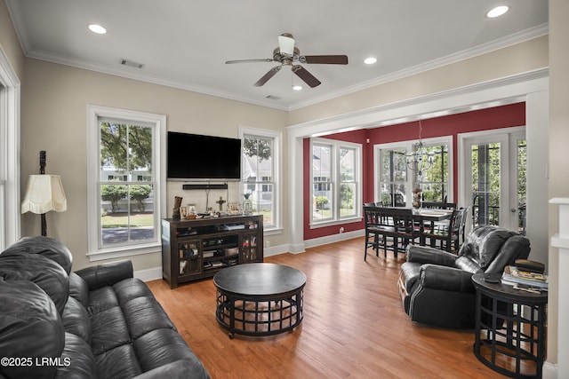 living room featuring plenty of natural light, visible vents, wood finished floors, and a ceiling fan