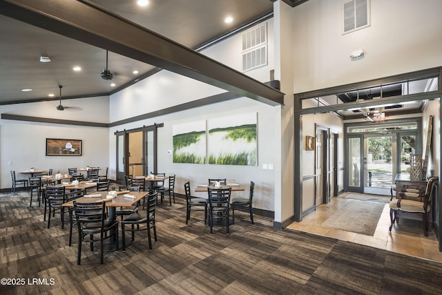 carpeted dining area featuring baseboards, ornamental molding, visible vents, and high vaulted ceiling