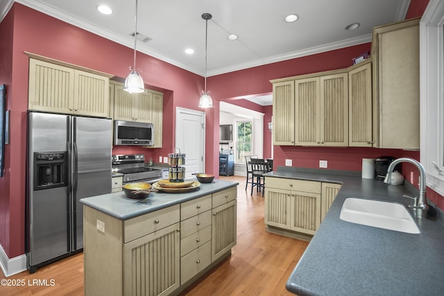 kitchen with pendant lighting, a sink, cream cabinetry, crown molding, and appliances with stainless steel finishes