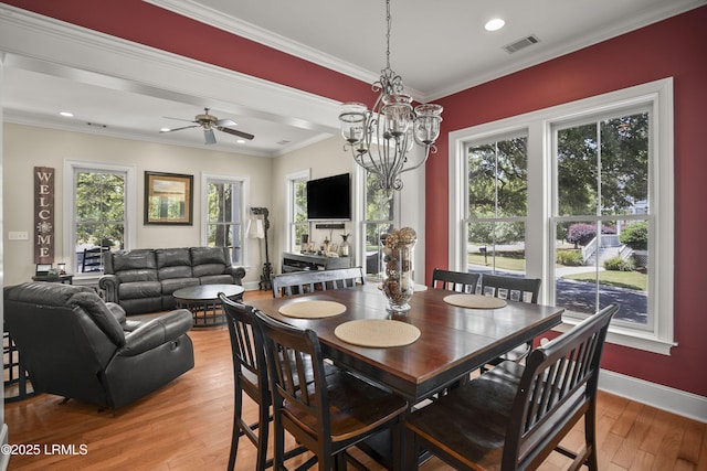 dining room featuring ceiling fan with notable chandelier, light wood-type flooring, visible vents, crown molding, and baseboards