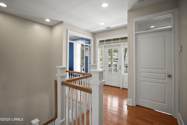 hall with wood finished floors, an upstairs landing, and recessed lighting