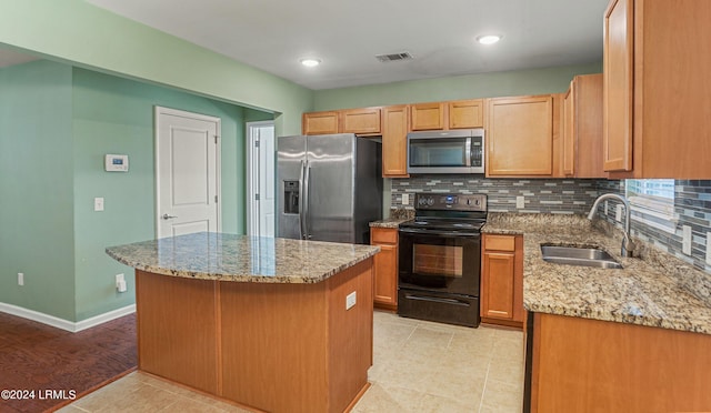 kitchen featuring stainless steel appliances, a sink, visible vents, backsplash, and light stone countertops