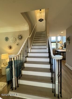 staircase with baseboards, ornamental molding, and wood finished floors