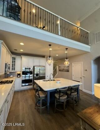 kitchen with a breakfast bar area, dark wood-style flooring, stainless steel appliances, light countertops, and a sink