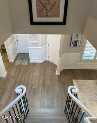 staircase with wainscoting, a decorative wall, and wood finished floors