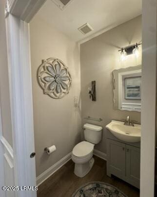 half bathroom with toilet, wood finished floors, vanity, visible vents, and baseboards