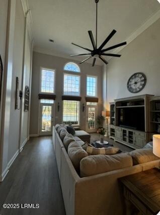 living room featuring baseboards, a high ceiling, ornamental molding, and wood finished floors