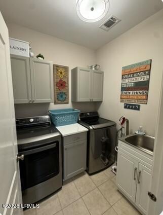 laundry room with light tile patterned floors, a sink, visible vents, cabinet space, and washing machine and clothes dryer