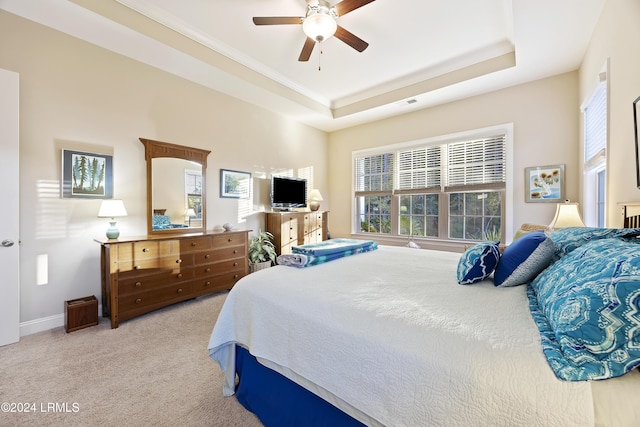 bedroom with light carpet, a raised ceiling, and ceiling fan