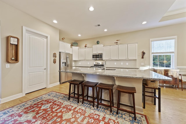 kitchen with appliances with stainless steel finishes, a breakfast bar, and white cabinets