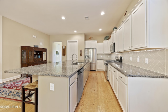 kitchen with stainless steel appliances, sink, an island with sink, and white cabinets