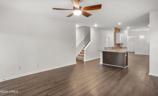 unfurnished living room featuring ceiling fan, dark hardwood / wood-style floors, and sink