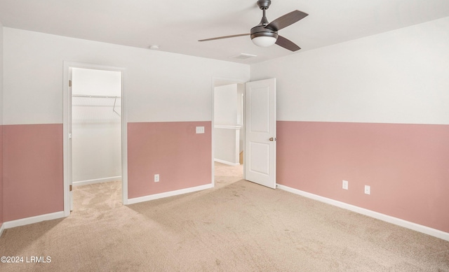 unfurnished bedroom with lofted ceiling, a spacious closet, light colored carpet, ceiling fan, and a closet