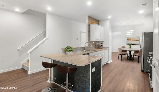 kitchen featuring sink, white cabinetry, stainless steel refrigerator, pendant lighting, and backsplash