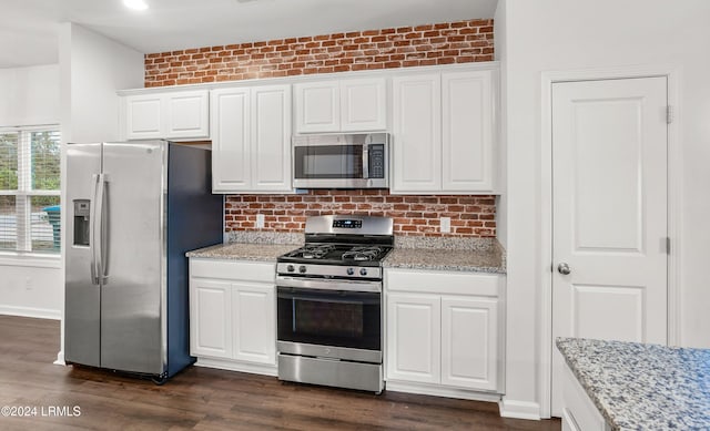 kitchen featuring stainless steel appliances, white cabinetry, and light stone countertops