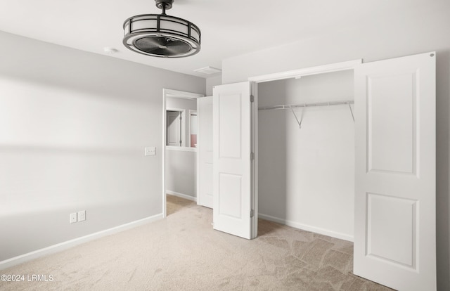 unfurnished bedroom featuring light carpet and a closet