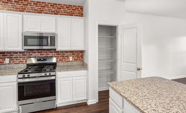 kitchen featuring stainless steel appliances, tasteful backsplash, light stone countertops, white cabinets, and dark hardwood / wood-style flooring