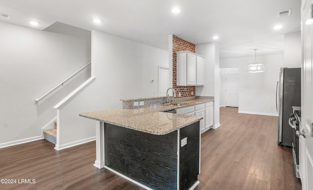 kitchen featuring sink, white cabinets, dark hardwood / wood-style flooring, hanging light fixtures, and light stone counters