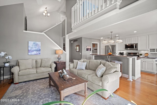 2009 Bluff Villas Rd, Saint Helena Island, SC 29920 - living room with a chandelier, light wood-style floors, a towering ceiling, recessed lighting, and baseboards