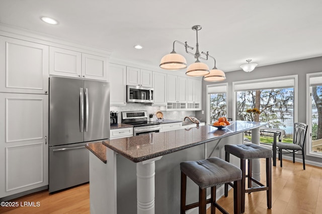 2009 Bluff Villas Rd, Saint Helena Island, SC 29920 - kitchen featuring stainless steel appliances, white cabinets, a kitchen breakfast bar, decorative backsplash, and a kitchen island with sink