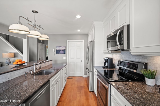 2009 Bluff Villas Rd, Saint Helena Island, SC 29920 - kitchen featuring appliances with stainless steel finishes, a sink, white cabinets, decorative backsplash, and light wood-type flooring