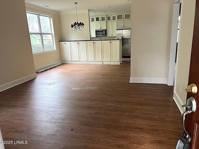 kitchen featuring hanging light fixtures, ornamental molding, freestanding refrigerator, dark countertops, and glass insert cabinets