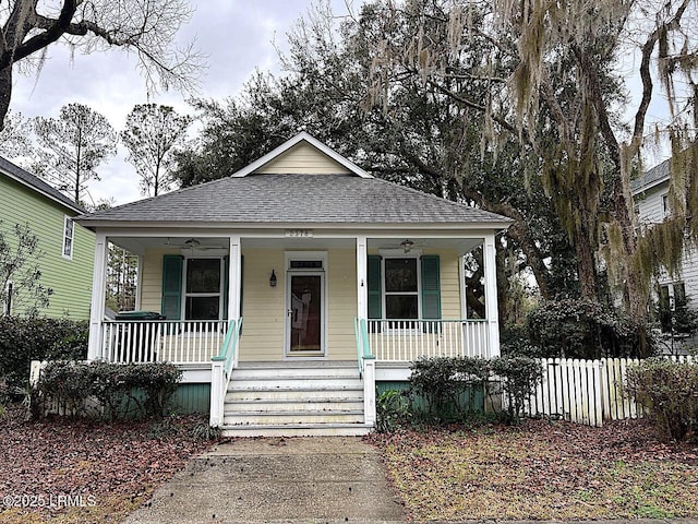 bungalow with a porch, a ceiling fan, and roof with shingles